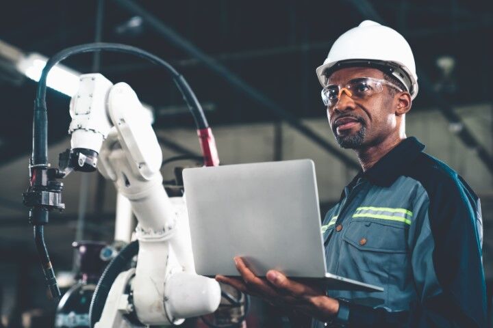 Manufacturing Cybersecurity Manufacturing employee holding a computer on the shop floor
