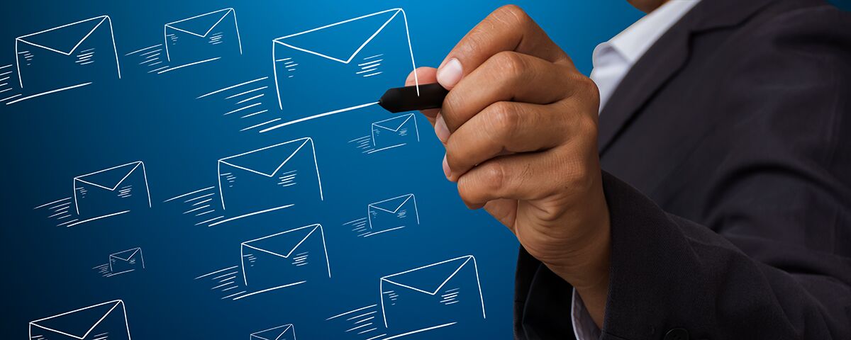 email-service-providers-2021 A man's hand draws outlines of email envelopes. Blue background
