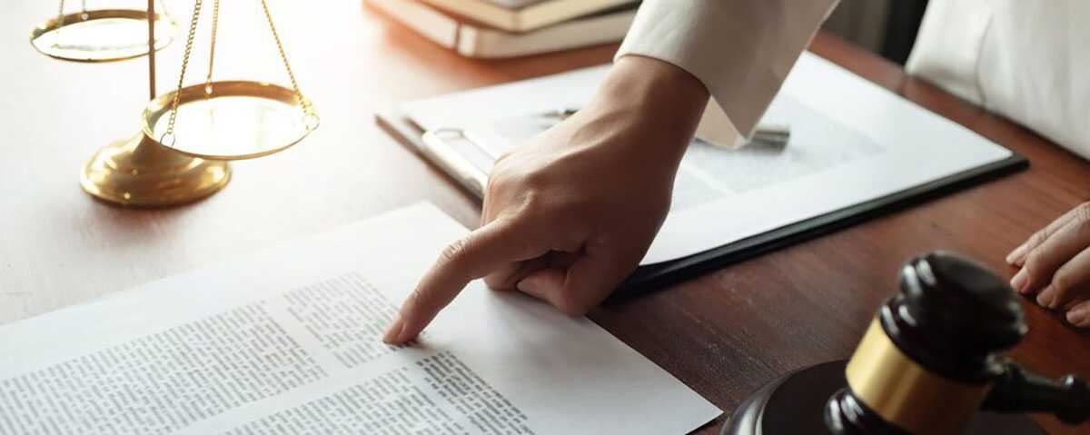 Lawyer hand pointing at paper on a desk