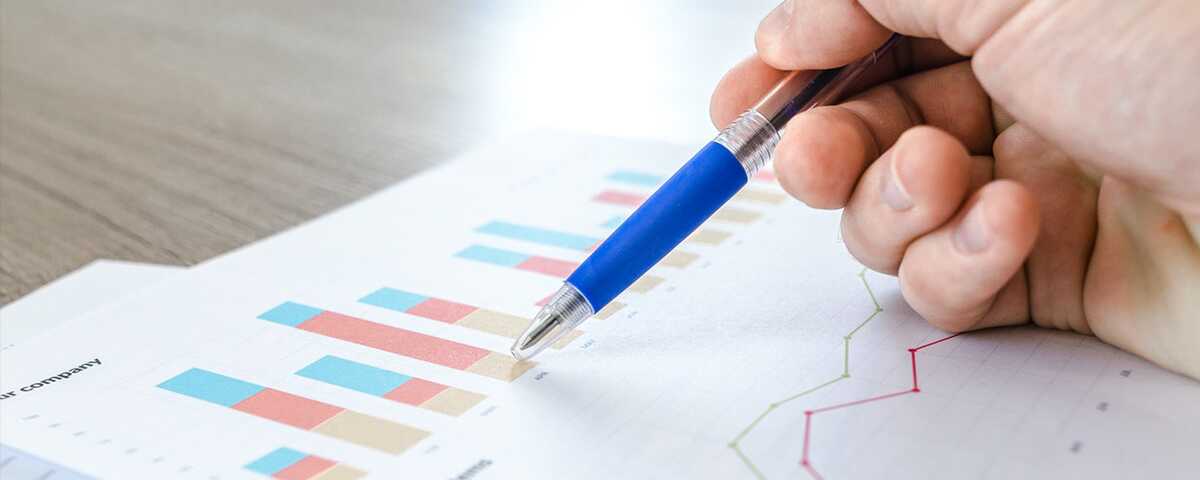 A hand holding a pen goes over the details on a printed graph