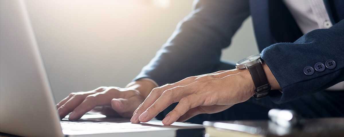 Photo of a man's torso while he uses a laptop