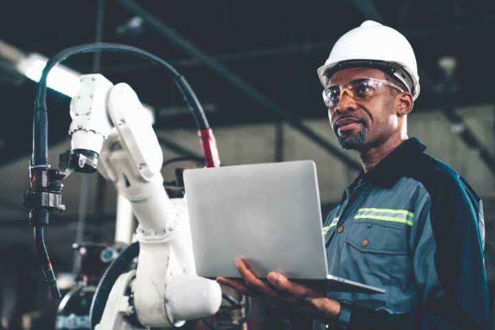 Manufacturing Cybersecurity Manufacturing employee holding a computer on the shop floor
