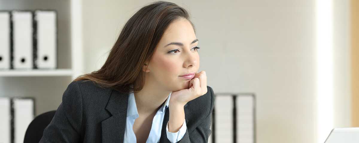 A woman in professional attire stares off-screen, distracted