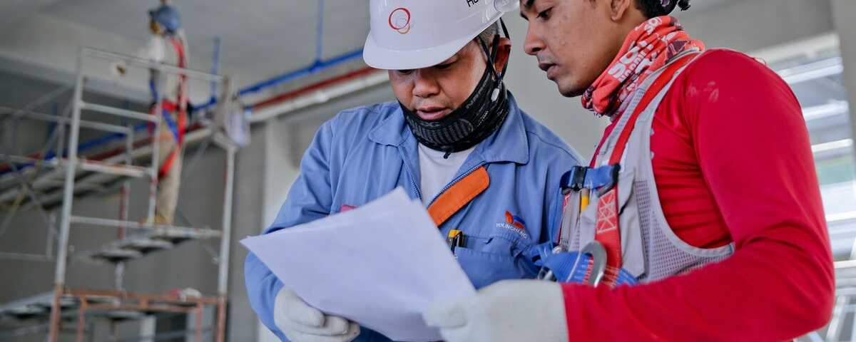 Two manufacturing employees review a sheet of paper